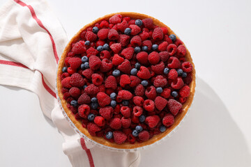 Berry pie and towel on white background, top view
