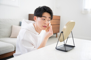 Beauty and beauty images of young men looking in the mirror and applying primer, foundation, etc.	