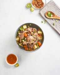 Enjoy a nourishing bowl of oxtail soup surrounded by vibrant veggies, herbs, and a tangy dipping sauce, perfect for sharing