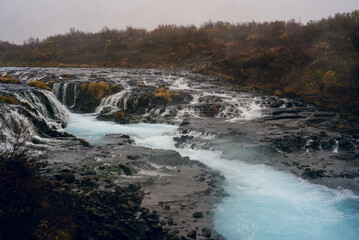 Brúarfoss Waterfall in Iceland, known for its stunning turquoise water, cascades over rugged volcanic rock, creating a mesmerizing and picturesque natural wonder