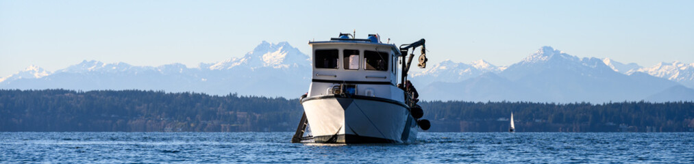 Scuba dive boat on calm Puget Sound waters with the Olympic Mountain Range in the background,...