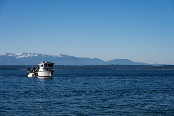Scuba dive boat on calm Puget Sound waters with the Olympic Mountain Range in the background,...