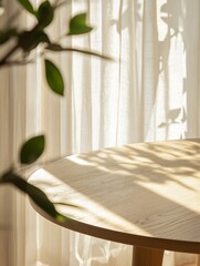 Sunlight illuminates a round wooden table near sheer curtains and plant.