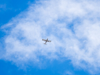 Small ultralight airplane with overhead wing and single propeller flying in sunset sky.