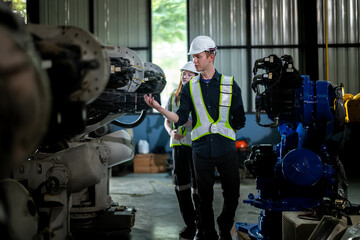 Factory engineers inspect on machine. Confident team mature businessman with laptop standing by robotic arm in industry businessman inspect at height technology for produce the electronic part device.