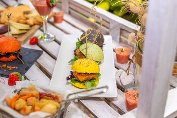 Gourmet burgers and appetizers presented on a wooden table.