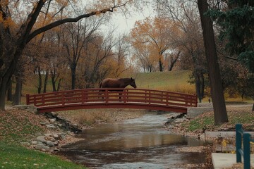 Obraz premium Brown Horse on Bridge Over Stream Surrounded by Autumn Trees