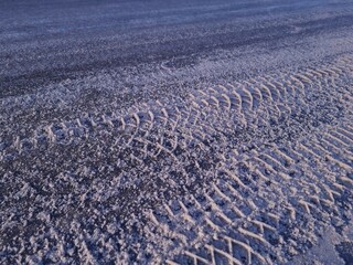 Morning sunlight illuminates car tracks in the snow. Winter background