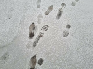 Asphalt road with footprints on freshly fallen snow
