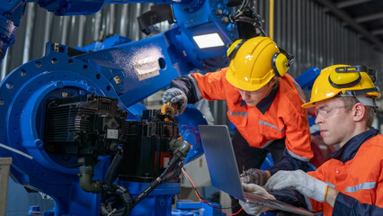 group of male engineer workers maintenance automatic robotic arm machine in a dark room factory....