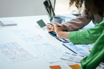 An African American businesswoman and a Caucasian woman collaborate at a desk, brainstorming...