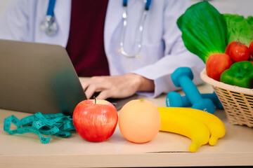 A male nutritionist sitting at a table, advising on healthy diets, promoting vegetable-based meals,...
