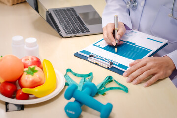 A male nutritionist sitting at a table, advising on healthy diets, promoting vegetable-based meals,...