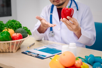 A male nutritionist sitting at a table, advising on healthy diets, promoting vegetable-based meals,...