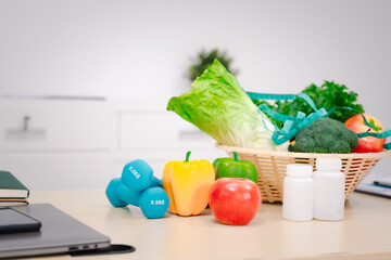 A nutritionist's table with a vegetable basket, fruits, pill bottles, and a dumbbell, symbolizing...