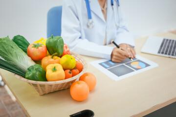 An Asian female doctor at her hospital desk works on a laptop, discussing the importance of eating...