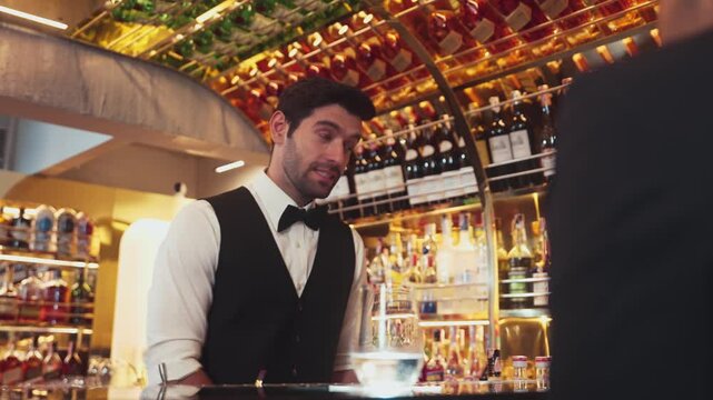 Focusing on smiling smart bartender preparing drinks at luxurious bar while engaging lively conversation with VIP customer at vibrant warm lighting atmosphere bottle bar and pub background. Vinosity.