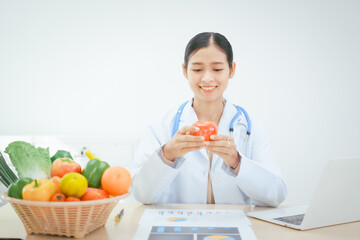 An Asian female doctor at her hospital desk works on a laptop, discussing the importance of eating...