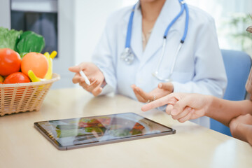 A young female nutritionist expert talks to a female patient at a table, recommending a healthy...