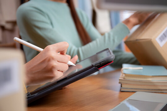 Closeup hand two young woman working while planning online business and checking order with writing on tablet at home, retail with online seller, startup business and cargo, shipping and service.