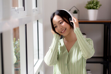 Portrait happy young woman wearing headphones listening music while standing with fun and enjoy in...