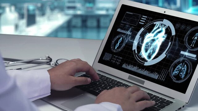 Close up of doctor typing and looking at laptop with human heart anatomy in computer screen at laboratory with blurring background. Medical worker checking and preparing for heart surgery. Remedial.