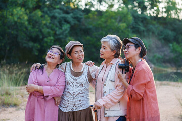 Senior Asian woman travels with close friend after retirement. Elderly embracing smiling standing closely together in scenic natural environment sharing joyful moment capturing happiness in friendship