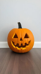 Carved Halloween pumpkin on hardwood floor against a light grey wall.  Ideal for autumn, holiday, or seasonal greeting cards