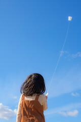 青空の下で凧揚げをする女の子