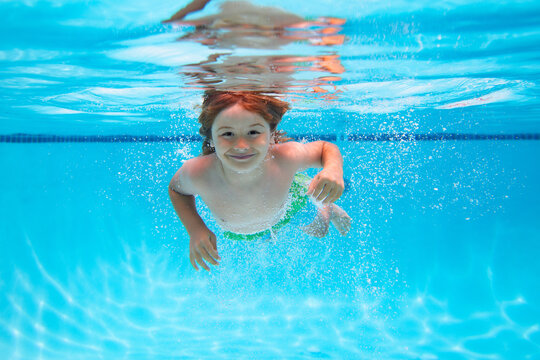 Child splashing in swimming pool. Underwater boy in the swimming pool. Cute kid boy swimming in pool under water. Active healthy holiday. - Powered by Adobe