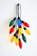 A cluster of brightly colored Christmas lights on a white background, adding festive color and glow