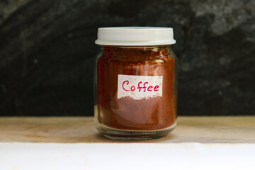 Coffee in a glass jar on a wooden table with a black background