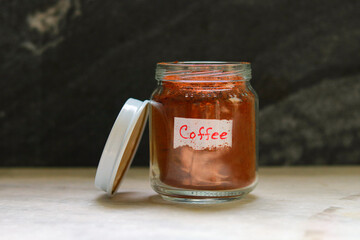 Coffee in a glass jar on a wooden table with a black background
