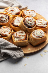 Delicious cinnamon rolls with white icing and almond flakes resting on wooden plate