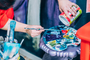 Close-Up Of A Painter’s Hands Mixing Vibrant Colors On A Palette In An Artistic Workspace - The...