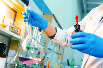 Researcher conducts chemical experiment with flask and reagent in laboratory setting