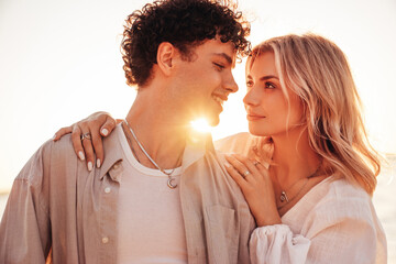 Smiling beautiful woman and her handsome boyfriend. Excited couple in casual clothes. Happy cheerful family. Female and man pose at sunrise over sea beach outdoors. Seaside in summer day