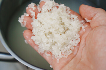 Rice is washed in a saucepan before cooking. grain processing before cooking rice dishes.
