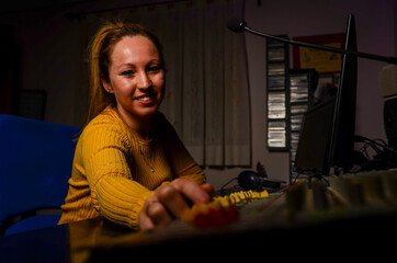 Female sound technician working on audio mixing console in music studio