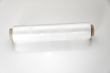 a roll of packaging stretch film on a white table. Convenient packing and transport material for groceries or moving.