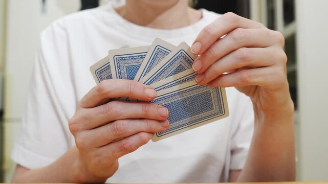 without a face. Hands of a man in a white t-shirt with cards during the game. gambling. A board game for spending leisure time with friends and family.
