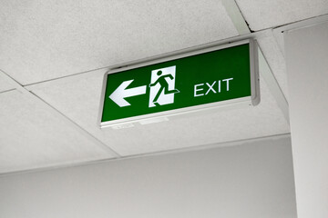 Clear exit sign directing individuals to the left in a well-lit indoor environment