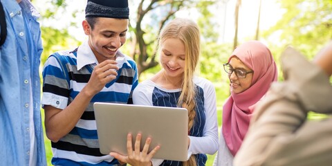 Diverse group of young adults enjoying outdoor learning. Smiling, engaged, and connected. Multicultural students sharing ideas and exploring together. Diverse students doing homework together.