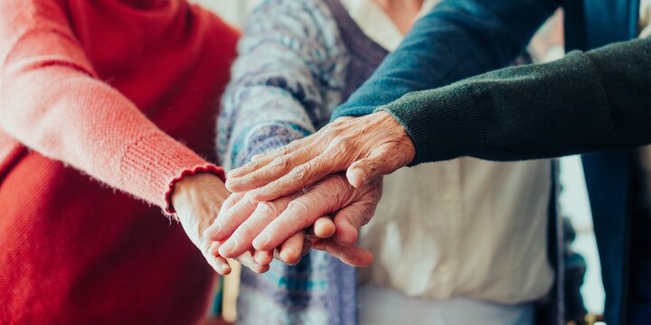 Close-up of diverse senior hands stacked together, symbolizing unity and teamwork. Hands of different ages and ethnicities show collaboration and support. Diverse old hands stacking in the middle.
