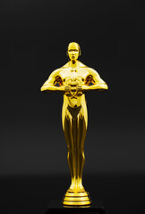 The golden statuette of the film award on a black background. awarding for achievements and...
