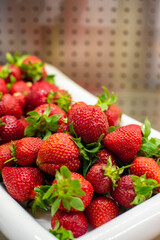 Organic red strawberries in heap in white bowl