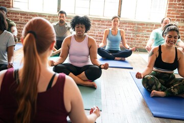 Diverse group of people practicing yoga indoors studio. People meditate on yoga mats in studio. Yoga class with group of men and women relax and meditate. Diverse people meditate in yoga class
