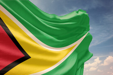 Waving flag of Guyana in blue sky. Guyana flag on pole for Independence Day. The symbol of the state on wavy fabric.
