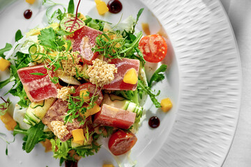 A close-up of a tuna salad, showcasing the variety of textures, from the flaky tuna to the crunchy greens and the creamy avocado.