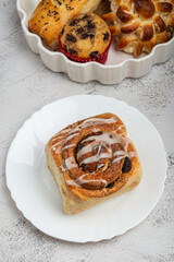 Top view of a freshly baked cinnamon roll with a generous swirl of icing, on a white plate